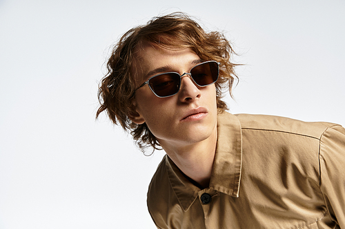 A handsome young man showcases a trendy autumn outfit while striking a pose in a modern studio setting.