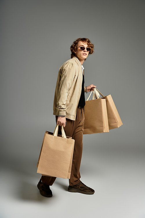 A handsome young man with wavy hair showcases his elegant autumn style while holding shopping bags.