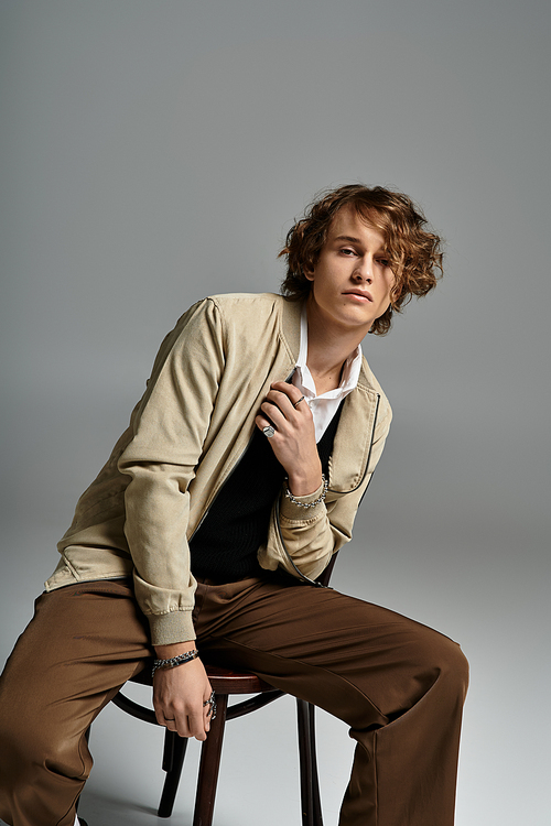 A charming young man poses confidently in a chic autumn outfit, exuding elegance and style indoors.