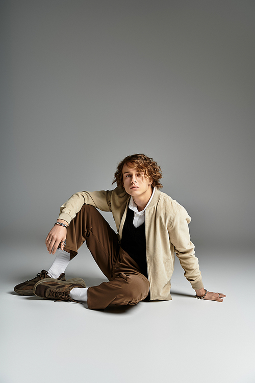 A handsome young man dressed in an elegant autumn outfit poses gracefully in a studio setting.