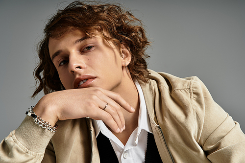 A handsome young man showcases a trendy autumnal look, posing thoughtfully in a stylish studio environment.