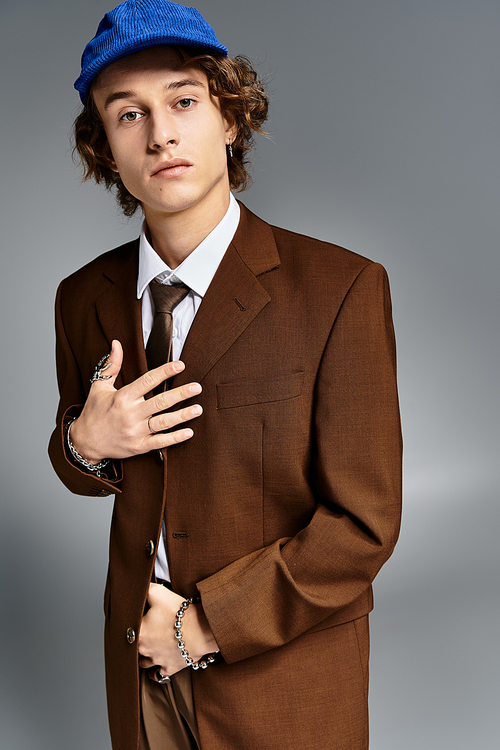 A fashionable young man showcases his unique style with a brown suit and blue baseball cap in a creative space.