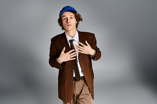 A young man in a brown suit and baseball cap showcases his unique style in a studio setting.