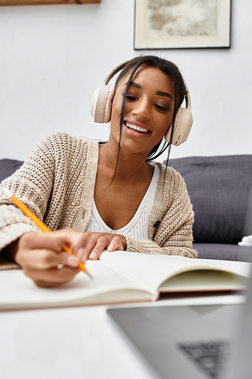 A cheerful young woman is deeply engaged in her studies at home, taking notes with a pencil.