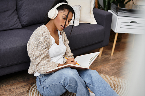 The young woman sits on the floor, dedicated to studying while immersed in a notebook.