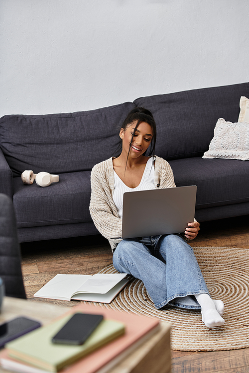 A young woman engaged in remote study, smiling while seated comfortably on the floor.