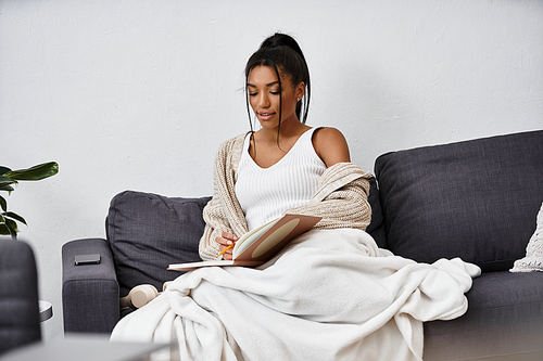 A beautiful young woman engages in remote studying on her couch, immersed in her books.