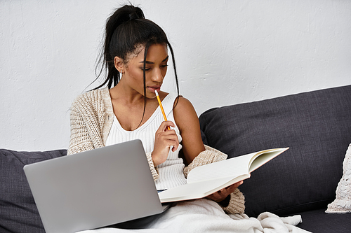 A beautiful young woman is engaged in remote study at home, focused on her notebook.