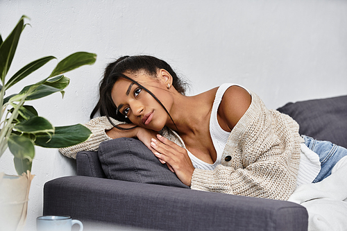 A young beautiful woman is thoughtfully studying at home in her cozy living space.