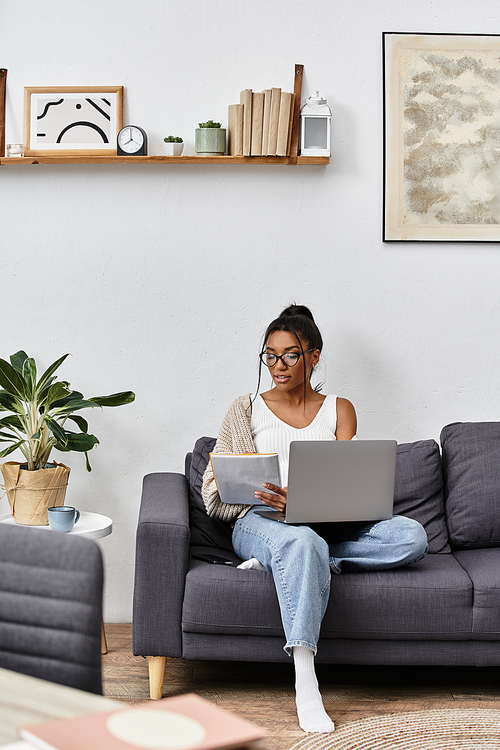 A young woman is comfortably studying on her laptop in a cozy, modern living room.