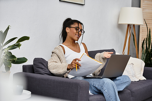 A young woman engages in remote study from her comfortable home environment, focused and relaxed.