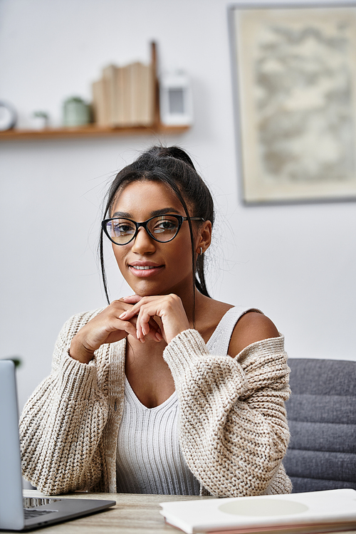 A beautiful young woman studies intently at her home desk, surrounded by a comfortable atmosphere.