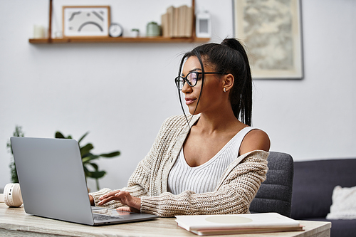 A beautiful young woman is engaged in remote learning, tapping away on her laptop at home.