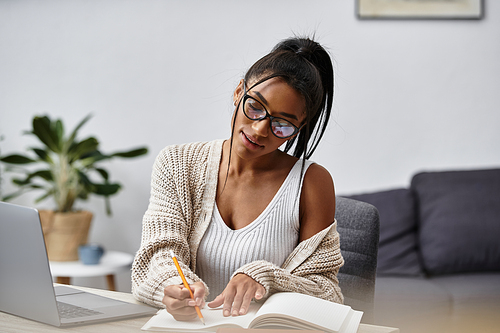 In a cozy home setting, a young woman focuses on her studies, jotting notes in her notebook.