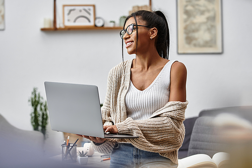 A beautiful young woman smiles while studying remotely from her comfortable home environment.