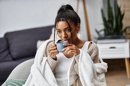 She sips her drink and immerses herself in studies, wrapped in a warm blanket on a chilly day.