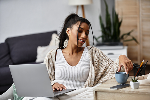 A beautiful woman is focused on her remote study session while relaxing at home.