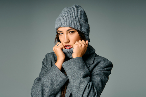 A young and attractive woman models fashion in a cozy gray outfit while showcasing her style.