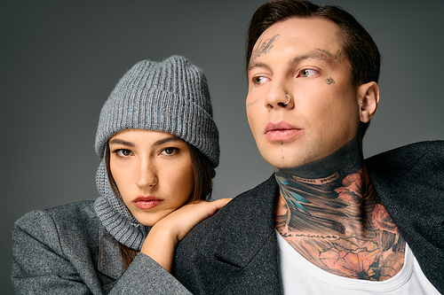 A stylish couple flaunts tattoos and trendy outfits in a modern setting.