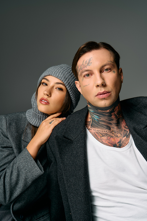 A trendy young man and woman showcase their fashion sense with tattoos and cozy attire.