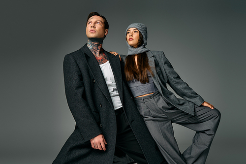 A young couple showcases modern outfits, exuding confidence and style in a creative studio setting.