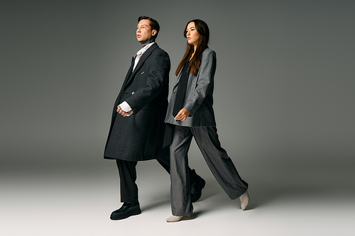 A young couple showcases contemporary fashion while walking together in a studio setting.