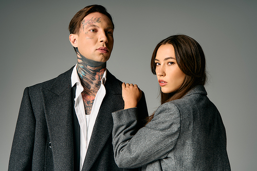 A young attractive pair showcases fashion with striking tattoos and confident expressions.