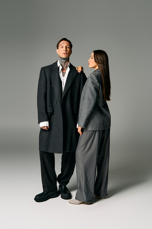 A young couple exudes confidence with their chic gray attire in a modern studio setting.