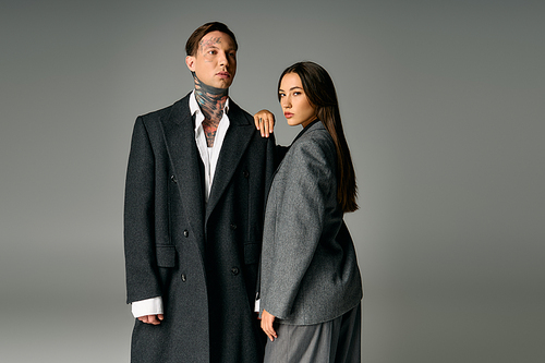 Attractive young couple stands confidently, showcasing modern fashion in a sleek studio.