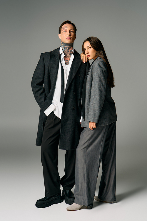 A fashionable duo displays contemporary attire in a sleek studio environment while posing.