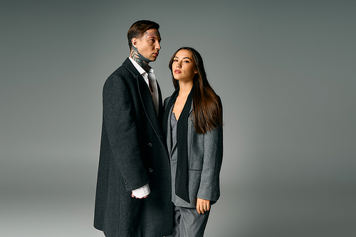 A young attractive couple poses intimately while showcasing elegant gray attire in soft lighting.