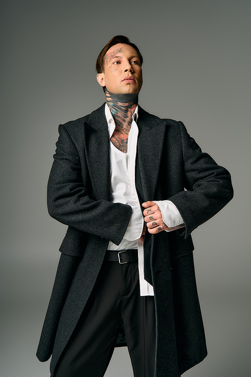 A stylish young person flaunts a dark coat and striking tattoos.