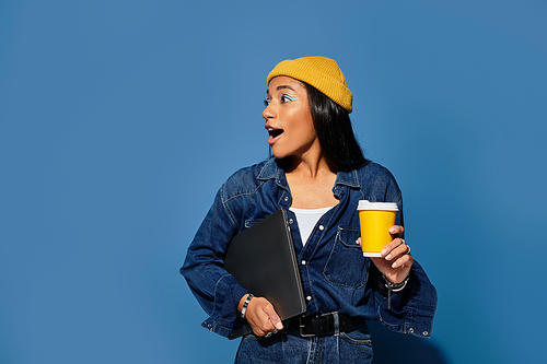 Dressed in chic autumn attire, a young woman surprises herself while holding a coffee cup.