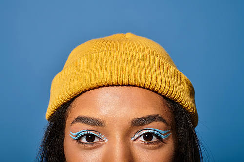 Sporting a chic beanie and bold eye makeup, a young woman embraces autumns warm vibes.