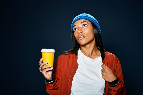 The young woman confidently showcases her warm autumn fashion while sipping coffee.