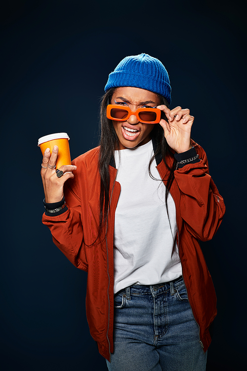 Sporting a vibrant outfit, the young woman expresses her style and warmth with a drink in hand.