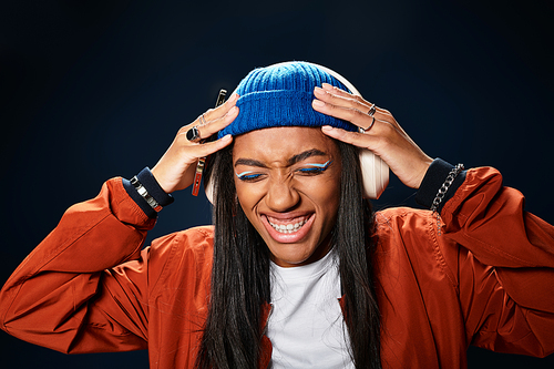 A stylish young woman in autumn attire expresses happiness while listening to music.