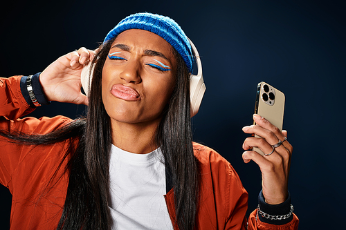 The young woman expresses joy as she listens to music, donning a trendy autumn outfit.