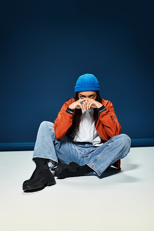 A young woman dressed in warm attire exudes style while seated on a smooth surface.