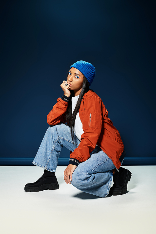 A young woman dressed in vibrant autumn clothing crouches gracefully with style and poise.