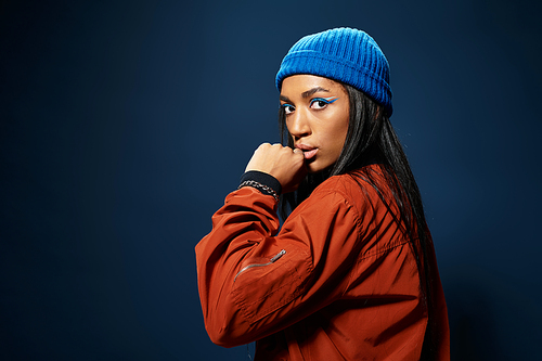 A young woman showcases her chic autumn style, confidently captured against a dark background.