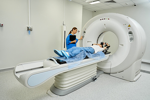 Female doctor guides patient into MRI machine for a medical examination in a hospital.