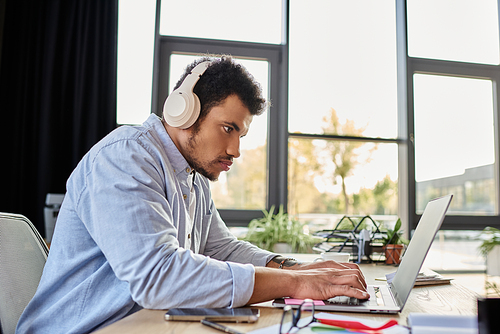 Handsome man engrossed in his work at a stylish desk with plants and natural light.