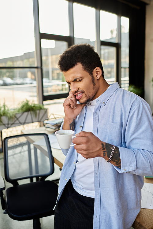 Handsome man ponders over a warm cup of coffee in a stylish office setting.