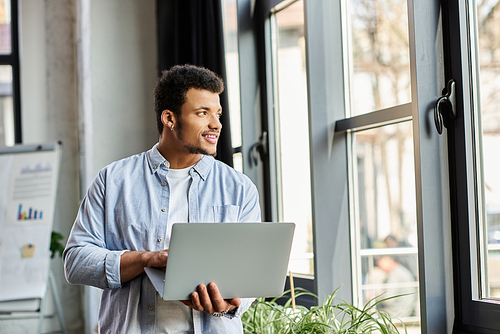 Focused individual engages with laptop indoors, smiling and enjoying the natural light.