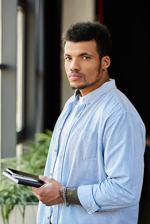 Confident individual with a charming look engages with his notebook while surrounded by greenery.