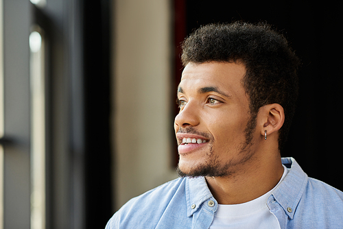 A confident young man with curly hair enjoys the view outside while smiling.