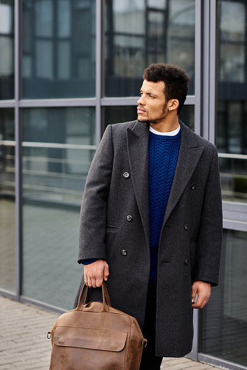 Confident man dressed elegantly strolls by sleek architecture on a sunny urban day.