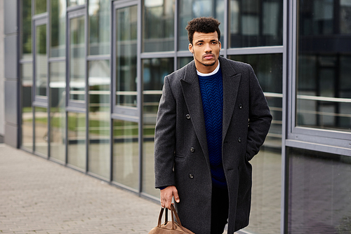 Young man in stylish coat strolls with a bag, showcasing confidence in the city.