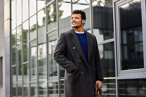 Handsome man stands casually with a smile, embracing the sunlight in an urban setting.